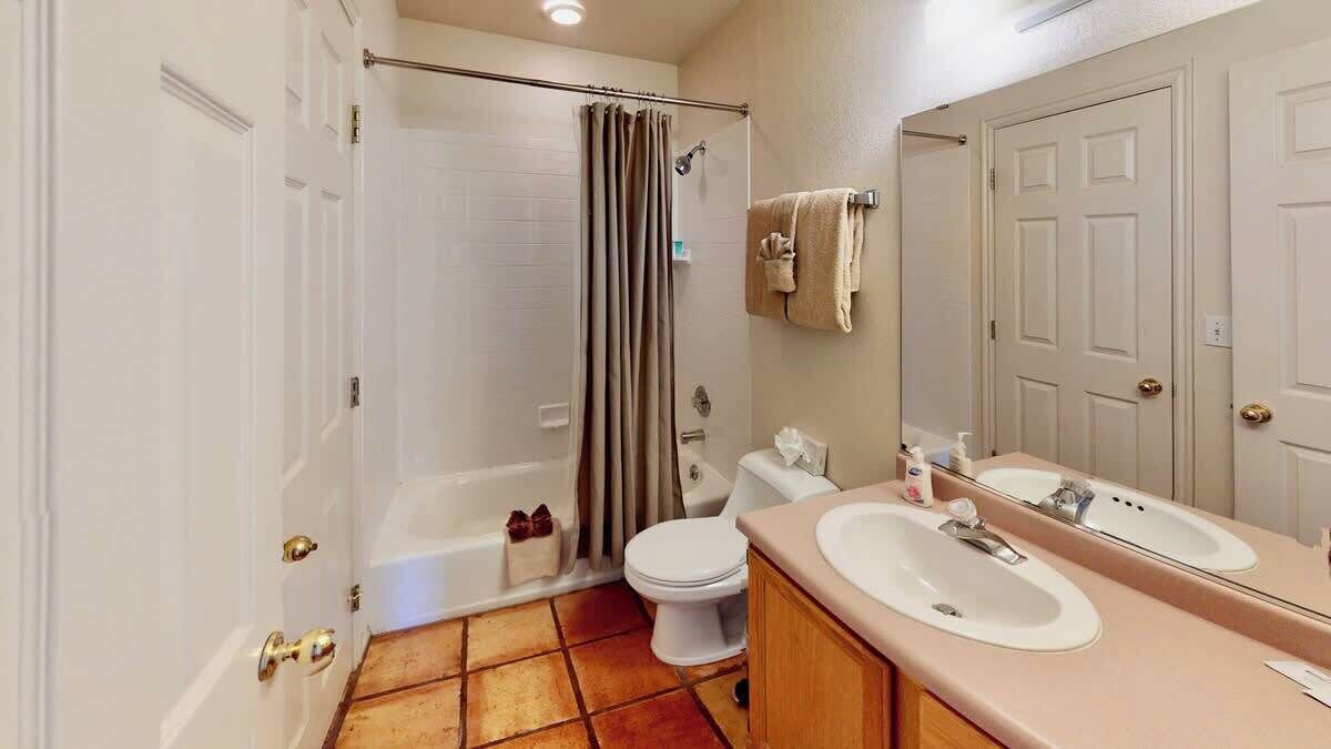 A bathroom with a shower, toilet, and two sinks.