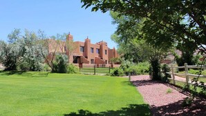 A building with a flat roof and multiple chimneys, surrounded by a well-maintained lawn and a wooden fence.
