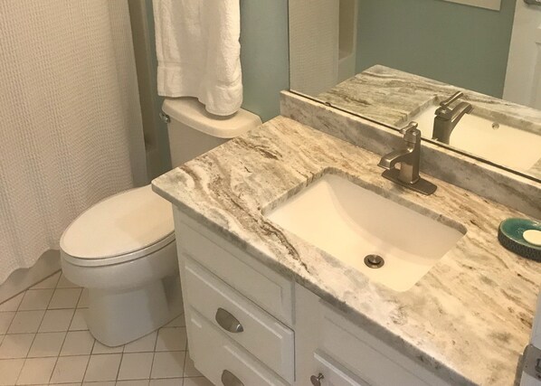 A bathroom with a toilet, a sink, and a mirror.