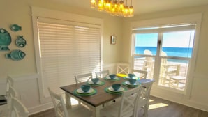 A dining area with a wooden table, white chairs, and blue plates. - Beach Front, dog friendly, 20 steps to Beach! (Cape San Blas)