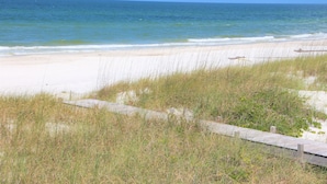 A beach with a wooden boardwalk leading to the water, surrounded by grass and sand. - Beach Front, dog friendly, 20 steps to Beach! (Cape San Blas)