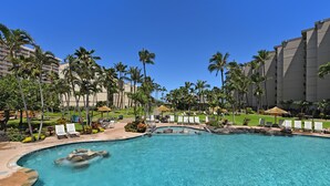 Ein Resort-Pool mit klarem Wasser, umgeben von Palmen und Liegestühlen.