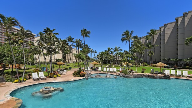 A resort pool with clear water, surrounded by palm trees and lounge chairs. - Time to Spoil Yourself!  Deluxe Ocean Front and Steps to N. Kaanapali Beach ~ (Lahaina)