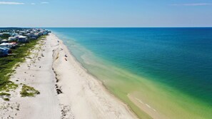 An aerial view of a beach with a row of houses along the shore.