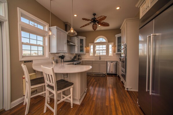 A kitchen with a central island, white cabinetry, a stainless steel refrigerator, and a ceiling fan.