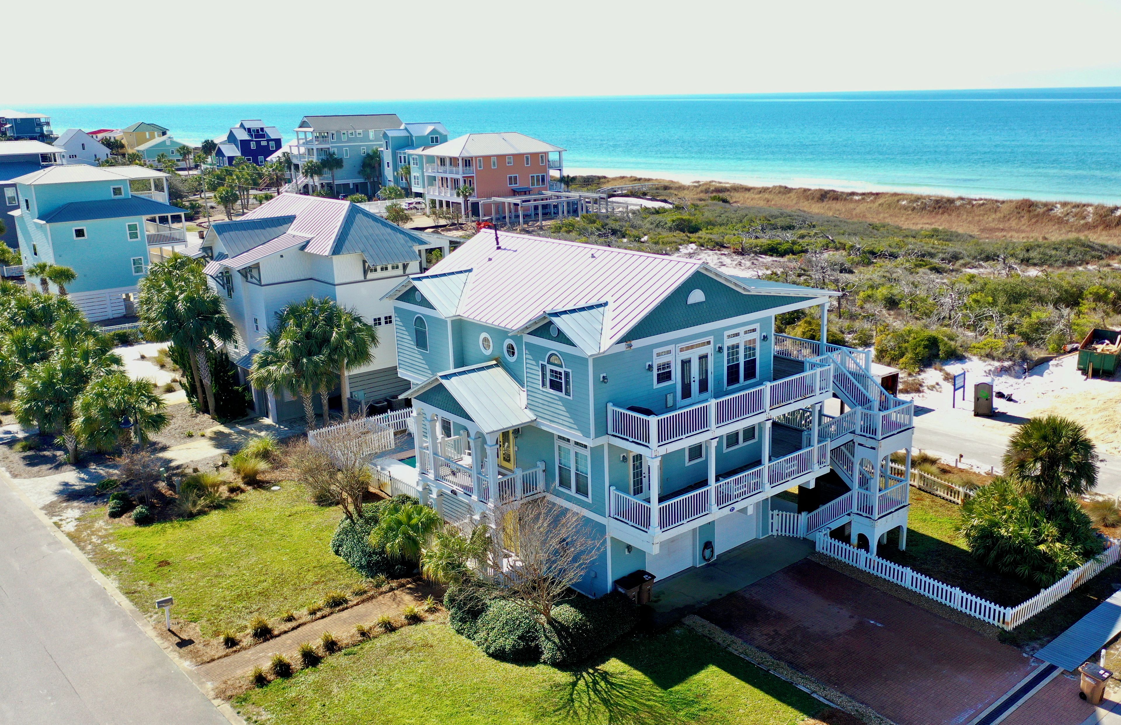 A large, multi-story beachfront property with a prominent balcony and a view of the ocean.