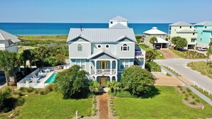 Une grande maison avec une piscine, entourée d’une végétation luxuriante et offrant une vue sur l’océan.
