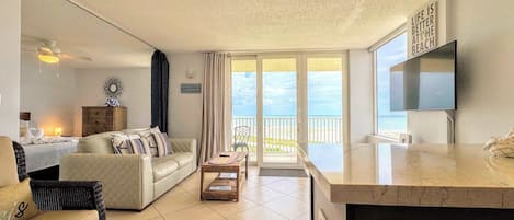 Un salón espacioso con sofá, mesa de comedor y vistas al mar a través de amplios ventanales.