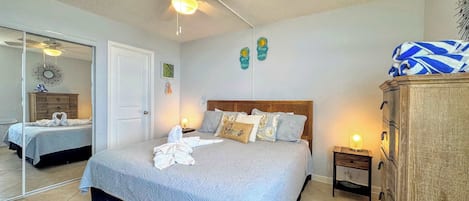 Un dormitorio con cama, ventilador de techo, cómoda y espejo.