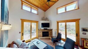 A spacious living room with a fireplace, large windows, and a ceiling fan. - Rim View Retreat - 14, Luxurious Stand-Alone 3 Be (Moab)