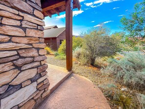 A stone exterior wall of a building with a wooden door frame and a covered porch.