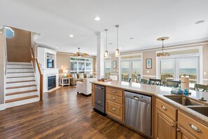 A spacious kitchen with a central island, stainless steel appliances, and a view of the ocean through large windows.