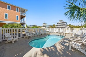 A pool area with lounge chairs and a pool, surrounded by a white fence, with buildings in the background. - 4 Bdrm Gulf Front Home w/Private Pool (Cape San Blas)