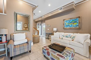 A spacious living room with a striped armchair, a white sofa, and a colorful ottoman. - 4 Bdrm Gulf Front Home w/Private Pool (Cape San Blas)