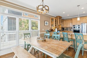 A spacious kitchen with wooden cabinets, a dining area with a wooden table and chairs, and a large window with blinds. - 4 Bdrm Gulf Front Home w/Private Pool (Cape San Blas)