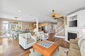 A spacious living room with a fireplace, a dining area with a view, and a kitchen with wooden cabinets. - 4 Bdrm Gulf Front Home w/Private Pool (Cape San Blas)