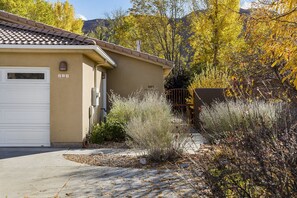 Set amidst lush vegetation, this home features a garage door and a small window above it, surrounded by a paved driveway.