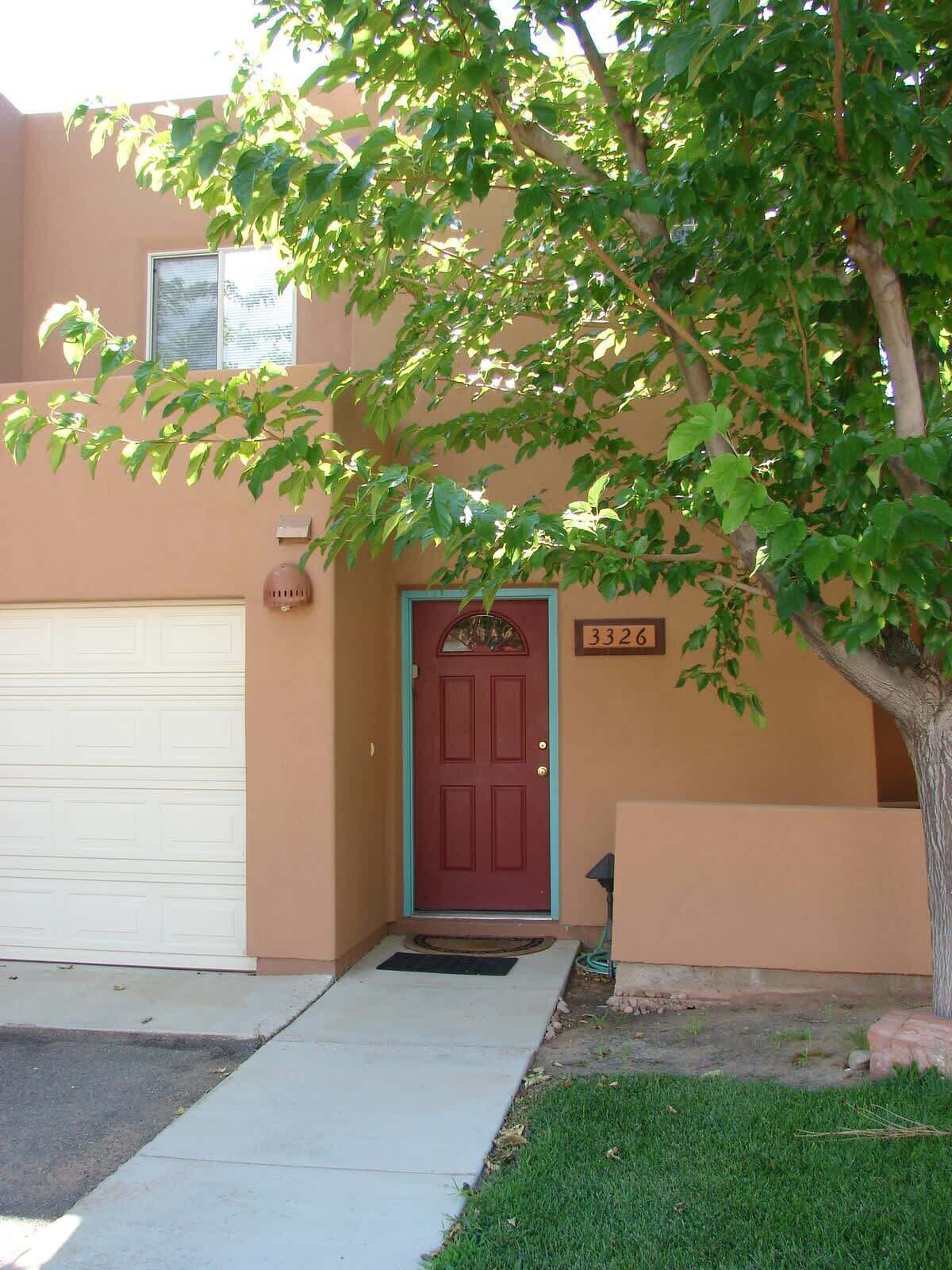 A residential house with a red door, a mailbox, and a number sign above the door.