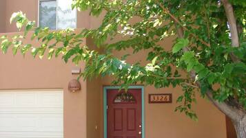 A residential house with a red door, a mailbox, and a number sign above the door.