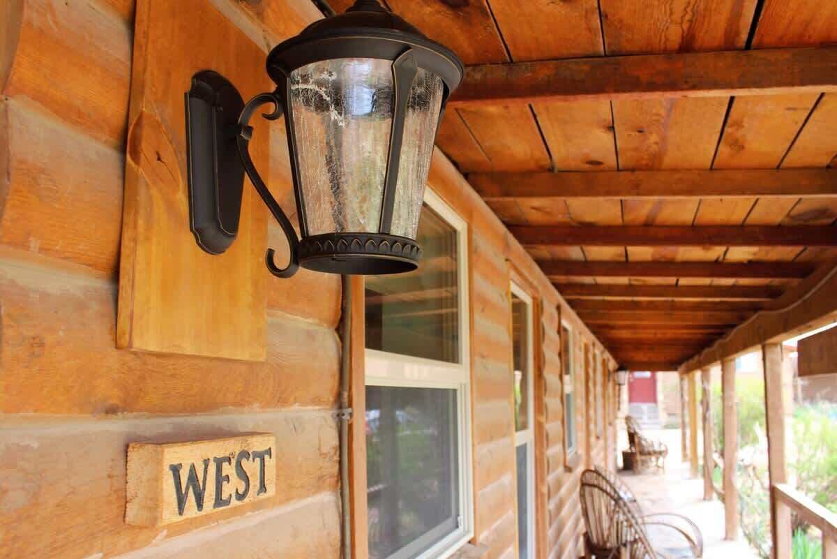 A wooden exterior wall with a sign labeled 'WEST' and a black lantern fixture.