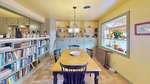Un comedor con una mesa de madera, sillas y una estantería llena de libros.
