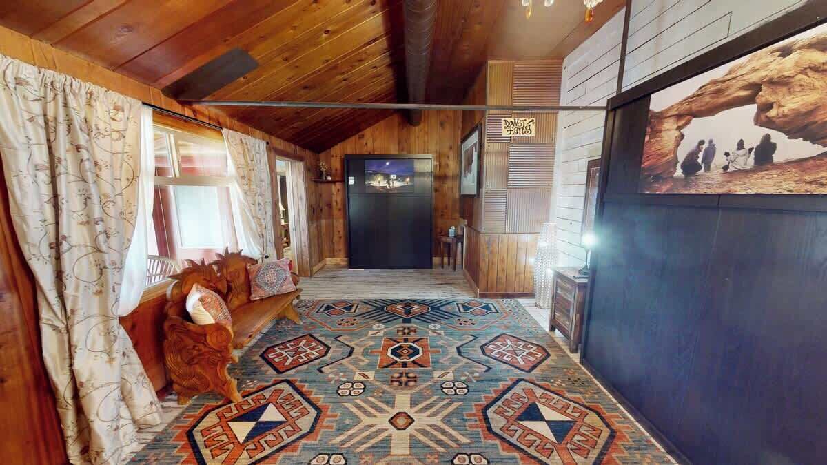 A wooden interior hallway with patterned carpet, a refrigerator, and a framed picture on the wall.