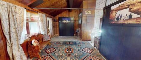 A wooden interior hallway with patterned carpet, a refrigerator, and a framed picture on the wall.