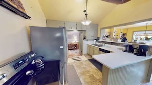 A kitchen with a stove, refrigerator, and island counter. - Pack Creek - The Lodge (Moab)