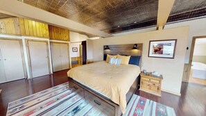 Un dormitorio con una cama grande, un armario de madera y un techo con vigas a la vista.