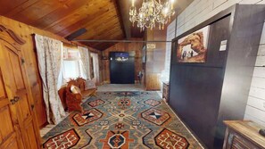A wooden interior with a patterned carpet, a chandelier, and a refrigerator.