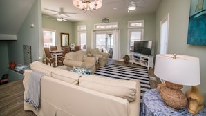 A living room with a sofa, TV, and ceiling fans. - La Bella Vita- Beautiful views of the gulf with private pool! (Port St Joe)