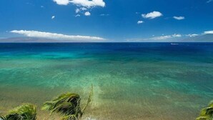 Una visuale limpida sull'oceano, con una terraferma in lontananza e una sola barca all'orizzonte.
