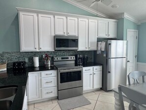 A kitchen with white cabinets, a stainless steel refrigerator, and a granite countertop. - 4bdrm Townhome on N CSB (Cape San Blas)