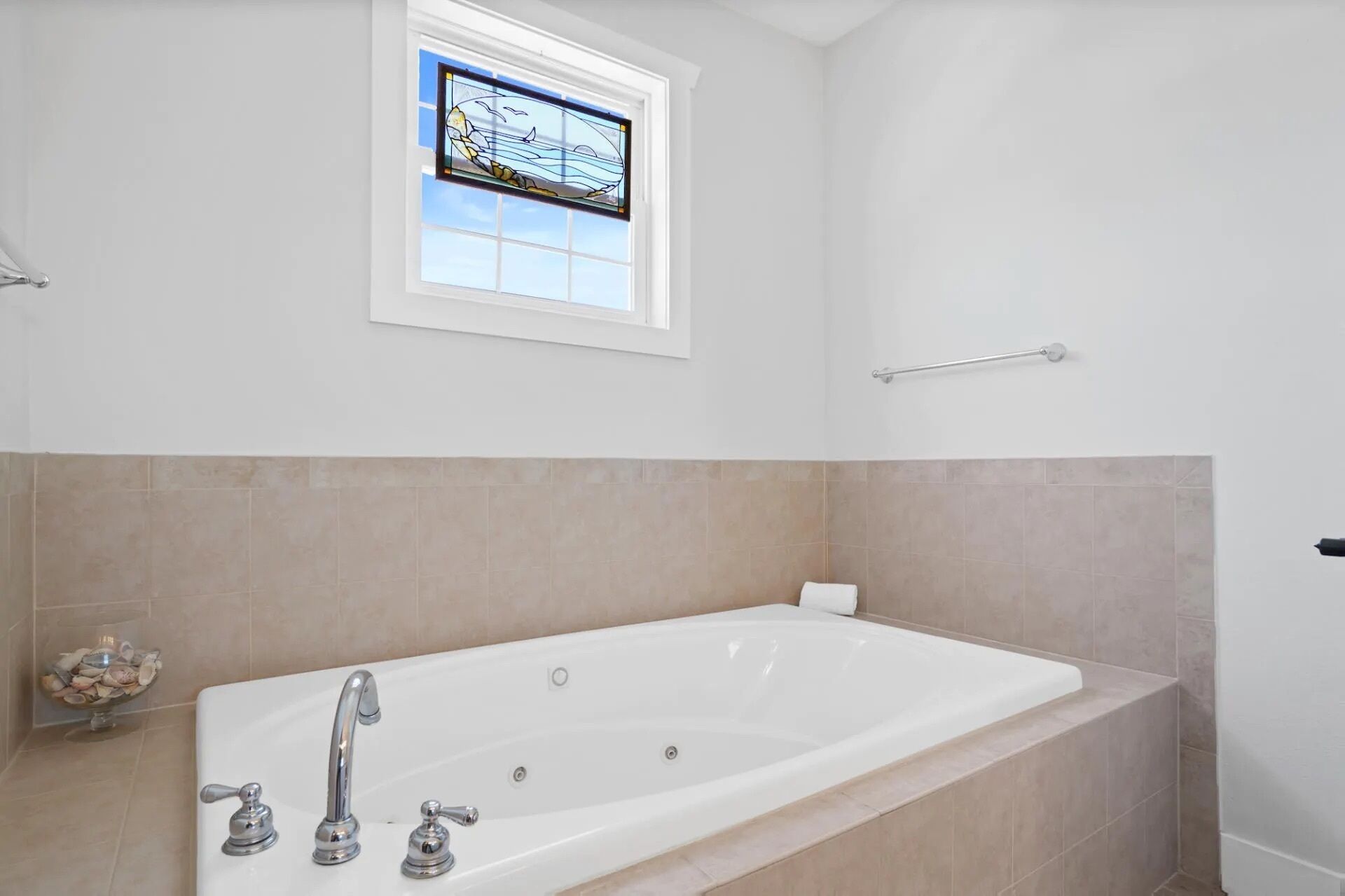 Un baño con una bañera grande, una ventana con vistas al mar y un perchero para toallas.