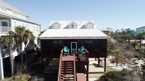 A two-story house with a balcony, a wooden deck, and a small outdoor seating area with chairs. - Beach Front Fun & Relaxation (Port St Joe)