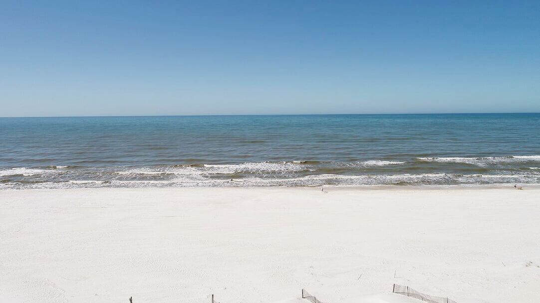 A beach with white sand and calm water.