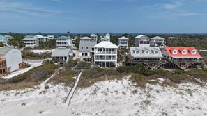 Zona residencial costera con varias casas frente a la playa, que cuentan con balcones y terrazas.