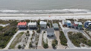 An aerial view of a coastal area with buildings, a beach, and a road.