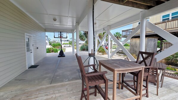 A covered patio area with a table and chairs, a basketball hoop, and a view of the surrounding neighborhood.