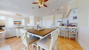 A spacious living area with a wooden dining table, white chairs, a sofa, and a ceiling fan. - Casual Beach Front with New Owners: Lots of updates! (Cape San Blas)
