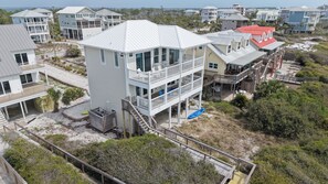A multi-story coastal building with balconies, a deck, and a view of the beach.