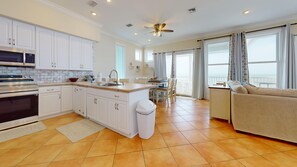 A modern kitchen with white cabinets, a built-in oven, and a large island.
