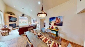 A spacious living area with a dining table, a red sofa, and a television mounted on the wall. - La Sal Overlook - S3, Best Views in Rim Village (Moab)