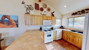 Una cocina con armarios de madera, microondas, estufa y lavabo.