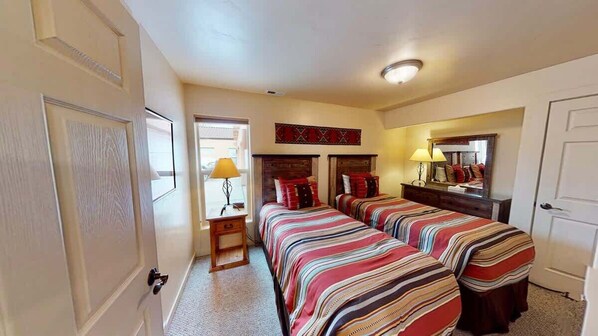 Habitación de hotel con una cama grande, una mesita de noche con lámpara, un aparador y un espejo.