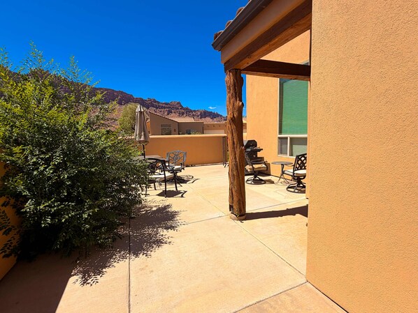 Une terrasse extérieure avec une table et des chaises, un barbecue et une vue sur une chaîne de montagnes.