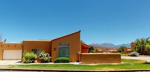 A single-story building with a flat roof, a garage, and a small front yard with a lawn and a few shrubs. - La Sal Overlook - S3, Best Views in Rim Village (Moab)