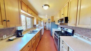 A kitchen with wooden cabinets, a stove, and a coffee maker. - Pack Creek - Ranch House, Hot Tub, Sauna, Cabin (Moab)