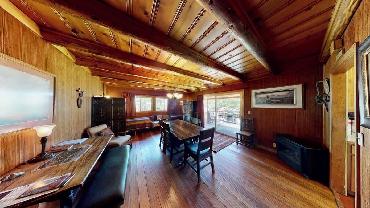Interior de madera con una larga mesa de comedor, bancos y una chimenea.