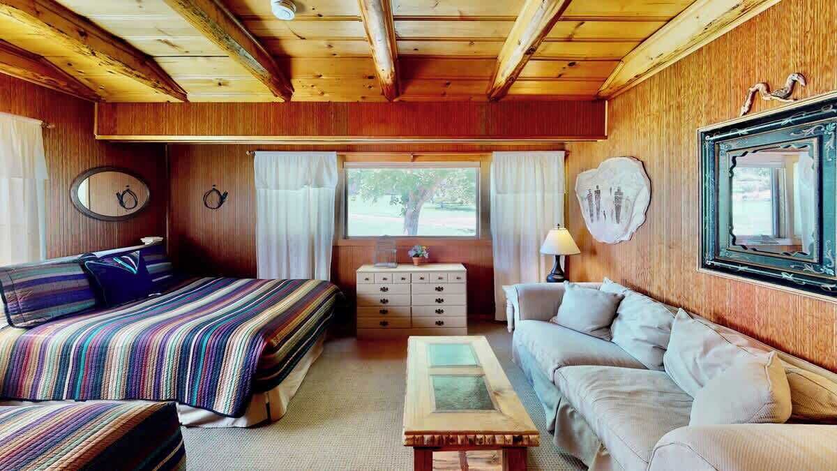 Una habitación acogedora con cama, sofá, cómoda y ventana con cortinas.
